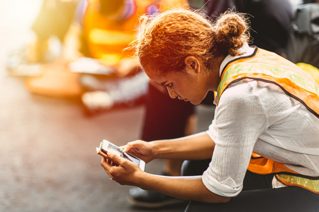 Worker in a safety vest on break, reading her phone
